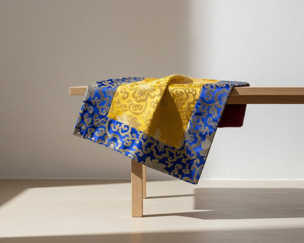 Blue and yellow patterned fabric draped over a wooden bench against a plain background
