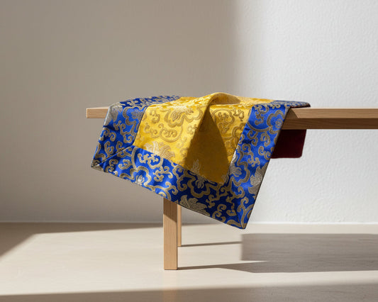Blue and yellow patterned fabric draped over a wooden bench against a plain background